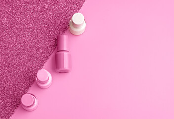 Obraz na płótnie Canvas Trendy design template with nail polish glass bottles on pink and sparkling background. Manicure concept. Mockup for your design with copy space. Flat lay style.
