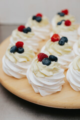 Dessert meringue with raspberry and blueberry on a wooden board. Dessert pavlova with fruits. 