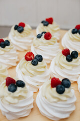 Dessert meringue with raspberry and blueberry on a wooden board. Dessert pavlova with fruits. 