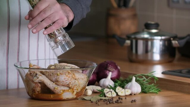 Pepper the Raw chicken legs for frying in glass bowl with marinade. Chicken marinade and spice mix process. Spices and sauce are mixed with chicken legs. Home kitchen, сlose-up, slow motion