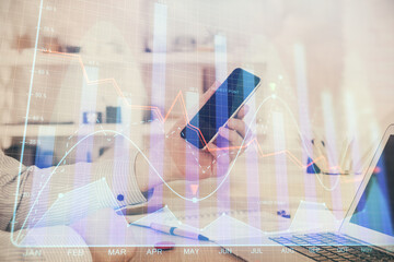 Double exposure of man's hands holding and using a digital device and forex graph drawing. Financial market concept.