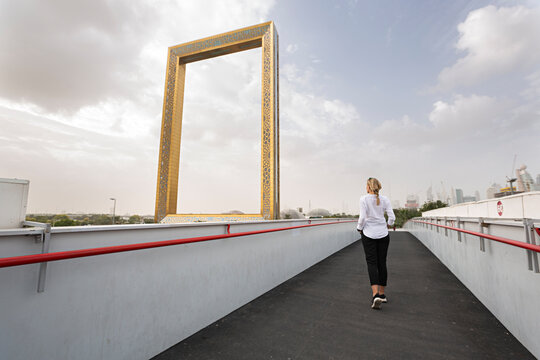 Mujer joven paseando por Dubái observando el cuadro gigante.