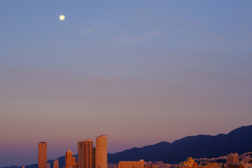 早朝、中秋の名月が六甲山に沈む。神戸市街地からの景観