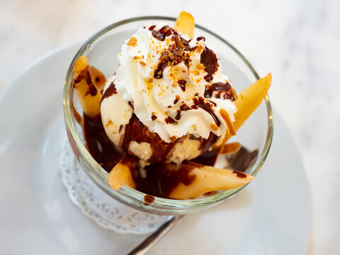 Poire belle Helene, peeled sliced pear poached in syrup served in dessert bowl with vanilla ice cream dressed with chocolate sauce. Popular French dessert..