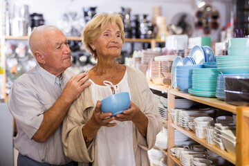 Portrait of an elderly couple in tableware store - making a selection of new plates and cups