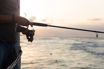 Man throwing fishing rod into the sea at the pier