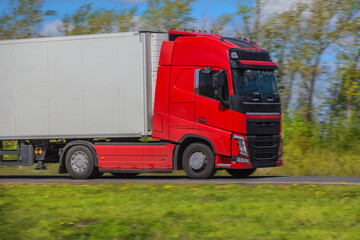 Red Truck Moves Along Country Road in summer.