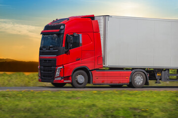 Red Truck Moves Along Country Road in summer.