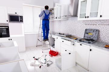 Workman Fixes A Hinge To A Kitchen Cabinet