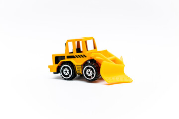Naklejka premium Colorful little mini yellow plastic tractor, truck, lorry, car toy isolated on white background mockup with copy space, toys for children, kids development, playing, childhood fun