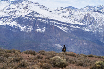 Obraz premium young man standing contemplating a snow capped mountain in the middle of the Andes Mountains of Chile