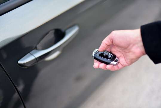 Unlock the car with a pop-up key. Female hand presses on the remote control car alarm system.
