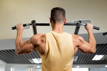 Fototapeta na wymiar Athlete muscular fitness male model pulling up on horizontal bar in a gym