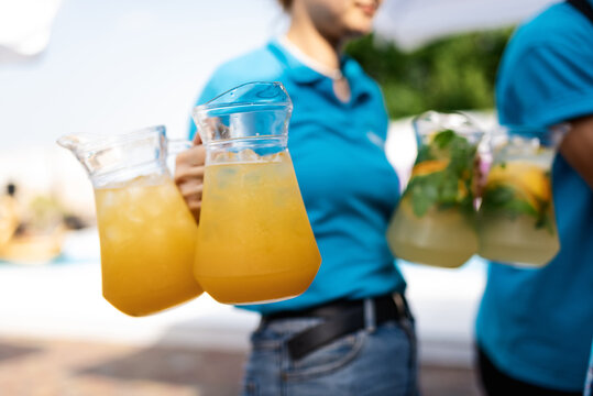girl waiter carries four carafes of lemonade - Powered by Adobe