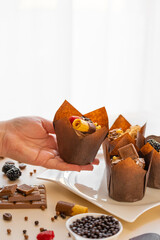  muffin in hand on the table with sweets and pastries background.Chocolate dessert. Assorted sweet table. Sweets and desserts. Baked goods and desserts