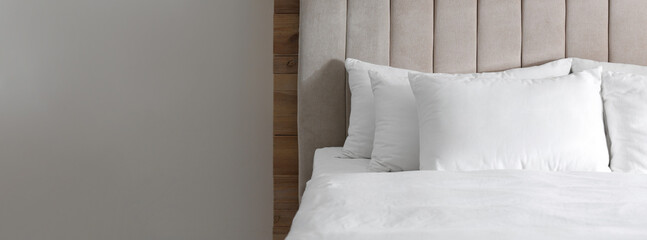Bed with soft pillows in room, space for text. Banner design