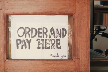 Sign "order and pay here  "sign used in restaurants and coffee cafe on wooden background.