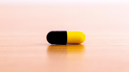 Close-up front view, Yellow-black pill capsule on the floor.