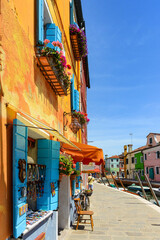 Fototapeta premium Bicycles parked in front of a brightly colored souvenir shop. Colorful houses in Burano Island. Famous travel destination, Venice, Italy