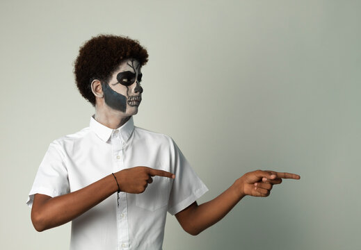afro latino teen painted catrin pointing to the side isolated