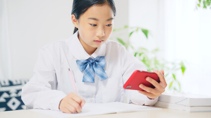スマホを見ながら勉強する女子学生　オンライン授業　eラーニング