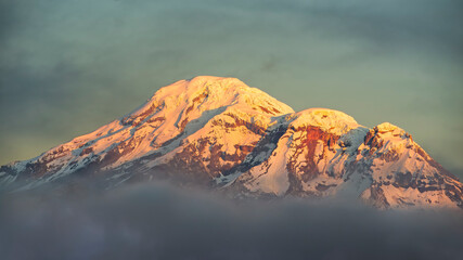 Chimborazo volcano emerging from a bank of clouds at sunrise