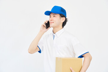 白背景でスマホで電話する宅配業者の男性