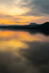 オレンジ色の夜明けの湖と山のシルエット。北海道の屈斜路湖。