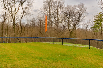 View of typical nondescript high school softball left outfield orange foul pole.  No people...