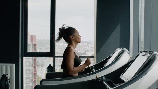 Morning cardio. Happy active african american lady running on treadmill at modern gym, enjoying workout, free space