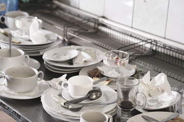 Dirty plates and glasses after a meal in the kitchen in the restaurant. Heap or pile of unclean...