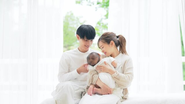部屋でくつろぐ赤ちゃんを抱いたカップル　家族イメージ