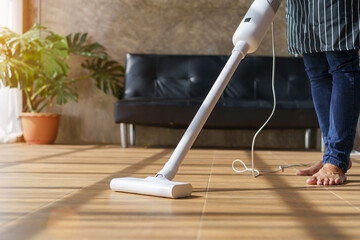 Fototapeta premium Man cleaning home living room with vacuum cleaner.