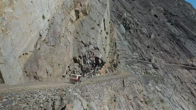 Aerial shot of vehicle on Fairy Meadows Road in Pakistan, second deadliest highway in the world, wide tracking drone shot