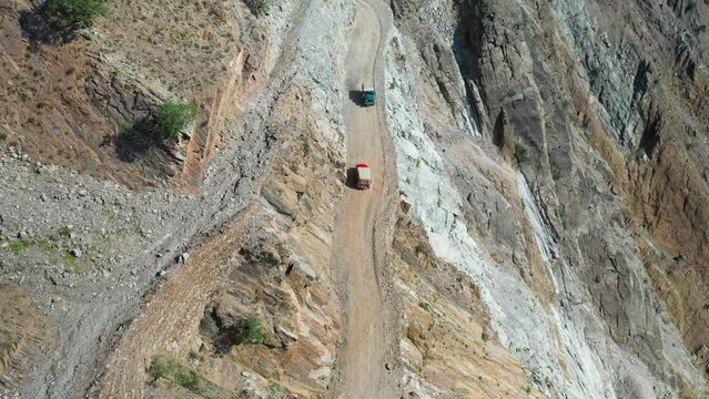 Epic drone shot of vehicles passing each other on Fairy Meadows Road in Pakistan, second deadliest highway in the world, wide aerial shot
