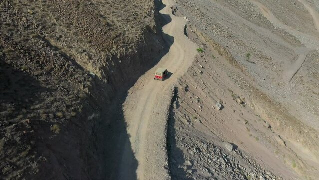 Aerial shot of vehicle on Fairy Meadows Road in Pakistan, second deadliest highway in the world, starting downward then revealing wide drone shot