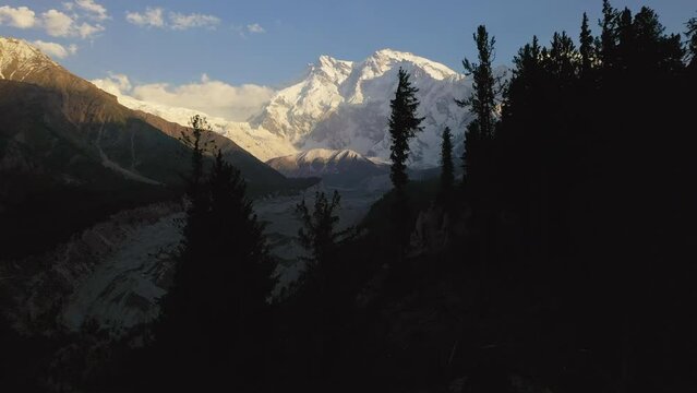 Drone shot of flying through trees towards Nanga Parbat, Fairy Meadows Pakistan, snow capped mountains, cinematic aerial shot