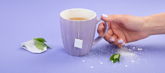 A cup of tea with sweetener and sugar.