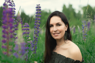 An attractive woman in a field with a summer bouquet of wildflowers Lupinus. Front view.