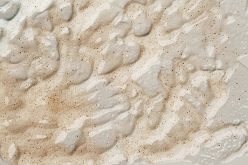 Beauty gel texture with particles. Beige uneven background with particles