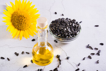 Sunflower seeds, oil in a bottle and a flower on the table. Organic products.