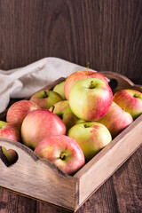 Fresh ripe apples in a box on a wooden table. Local seasonal fruits. Vertical view