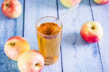 Organic homemade apple juice in a glass with a straw and fruits on the table