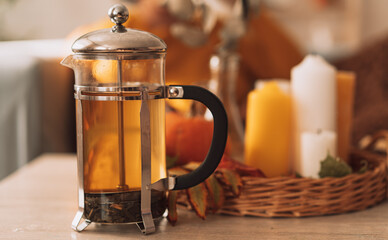 Herbal tea brewed in a teapot in front of burning candles and pumpkin.