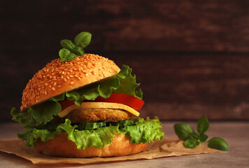 fresh hamburger with cutlet, cucumber, tomato and salad on a wooden board and dark background