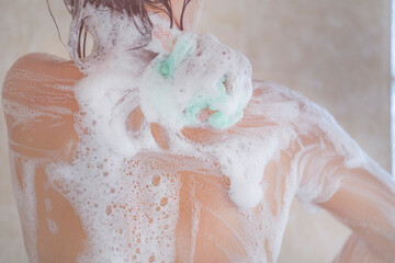 Woman showering. Headshot, Asian woman taking a shower. Cropped image of beautiful naked young woman rubbing body with foam and taking shower in bathroom.
