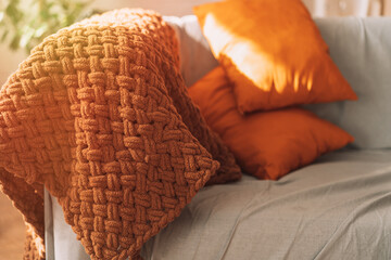 Orange pillows and a brown plaid on a gray sofa.