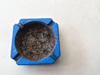 a photo of an ashtray for a smoker. blue and dirty