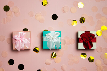Colorful gift boxes over the pink background with glitter.