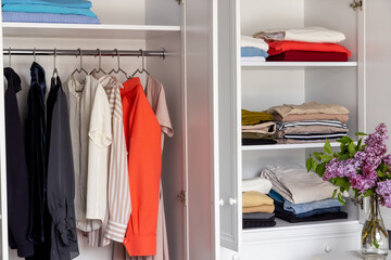Modern dressing room, neatly hung clothes on hangers and shelves in the closet